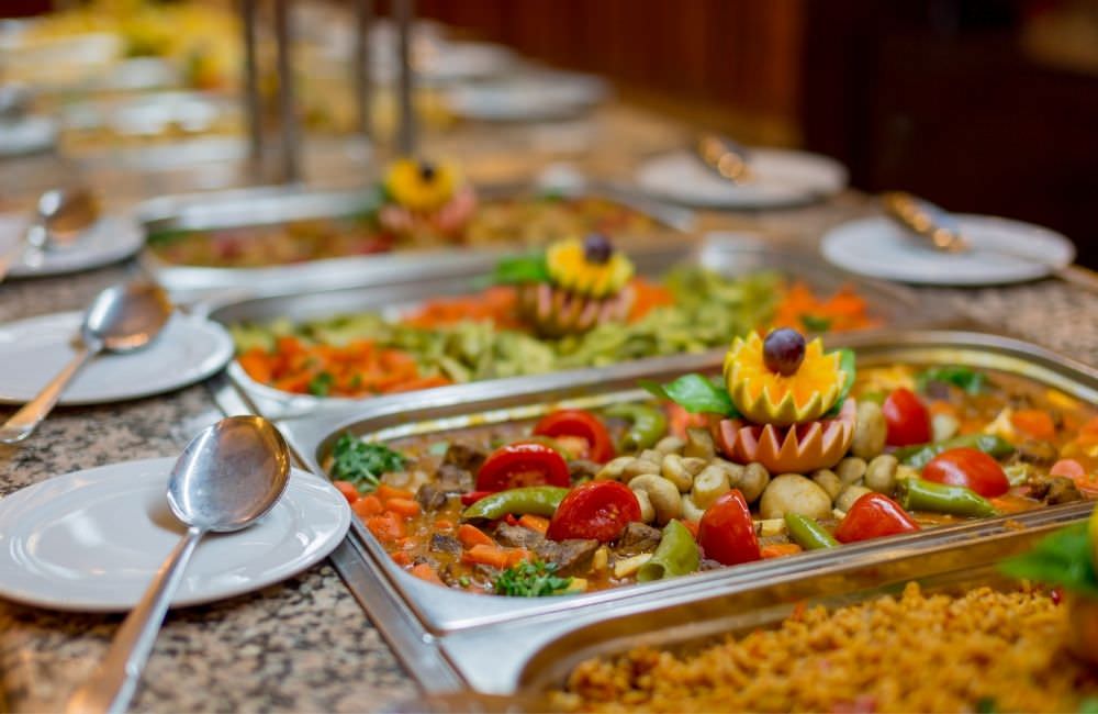 Warme Speisen in Warmhaltebehältern am Catering-Buffet