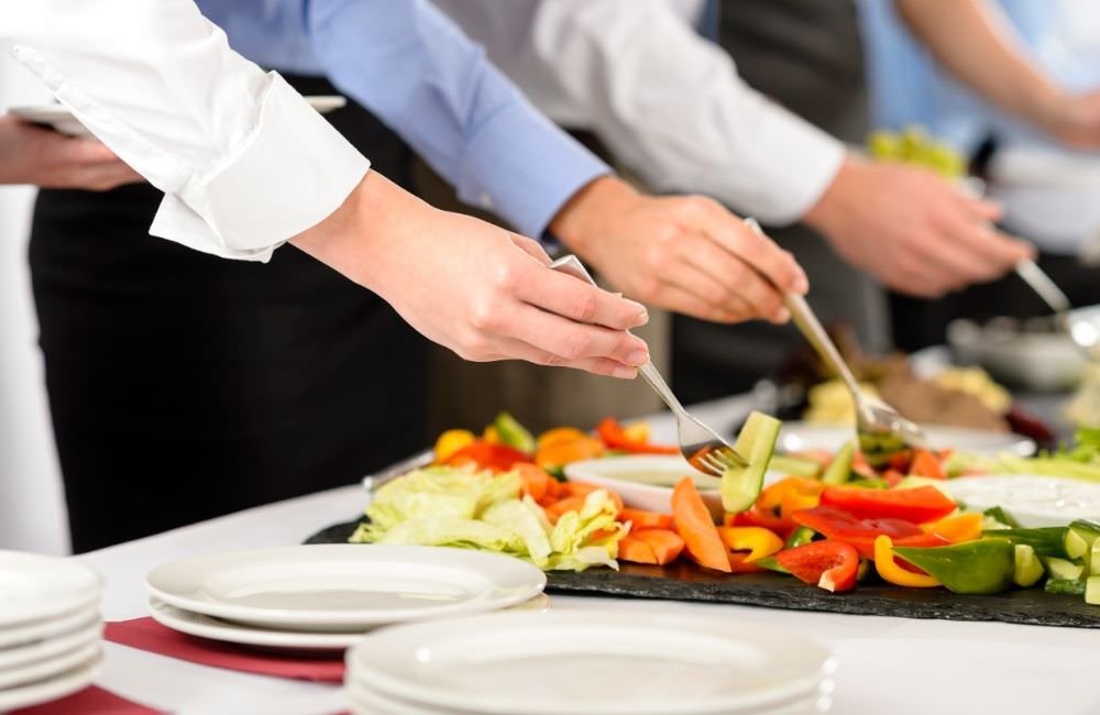 Servicekräfte richten Salat und Beilagen am Buffet für eine Firmenveranstaltung an