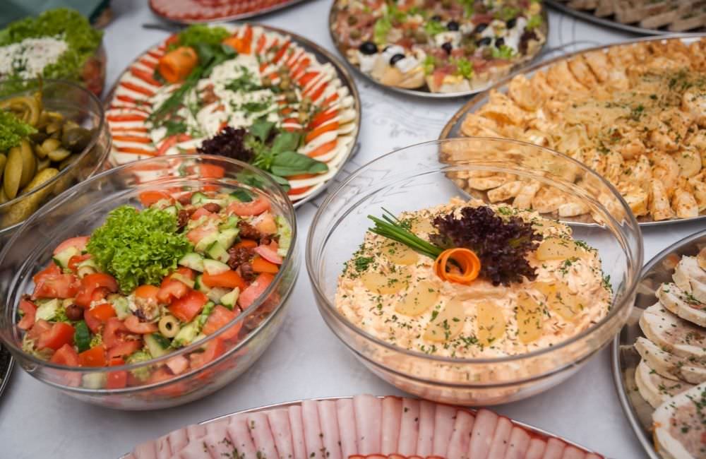 Salatschüsseln und Platten mit Aufschnitt auf einem Catering-Buffet