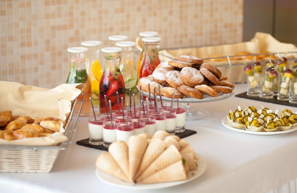 Fingerfood, Dessertgläser und Gebäck auf einem Empfangsbuffet